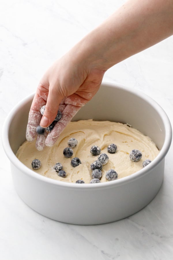 Sprinkling some flour-coated blueberries on top of the first layer of batter.