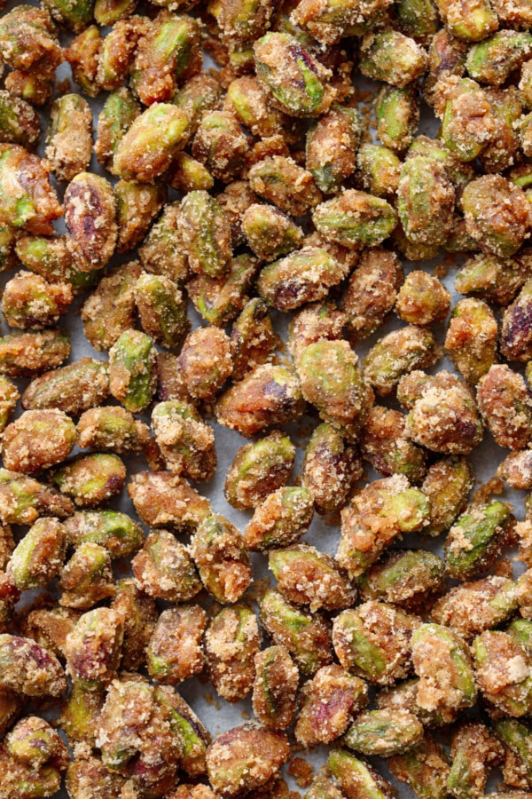 Closeup textural of spiced candied pistachios on a baking sheet.