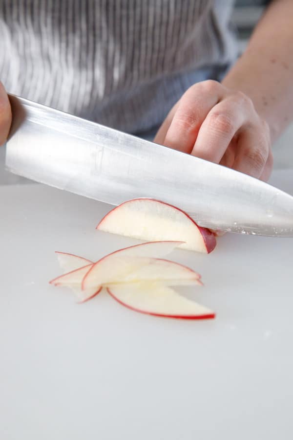 Slicing a red apple into paper thin slices.