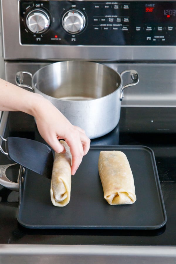 Flipping burritos with a spatula after toasting on one side.