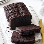 Sliced Chocolate Olive Oil Loaf Cake with drizzle of chocolate glaze on a wire baking rack