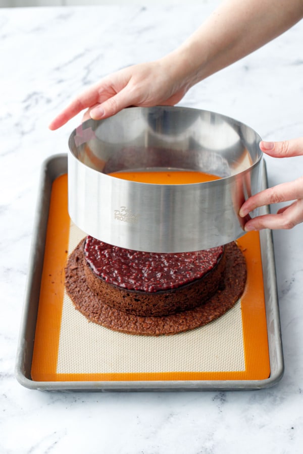 Placing an 8-inch pastry ring around the base and cake layers.