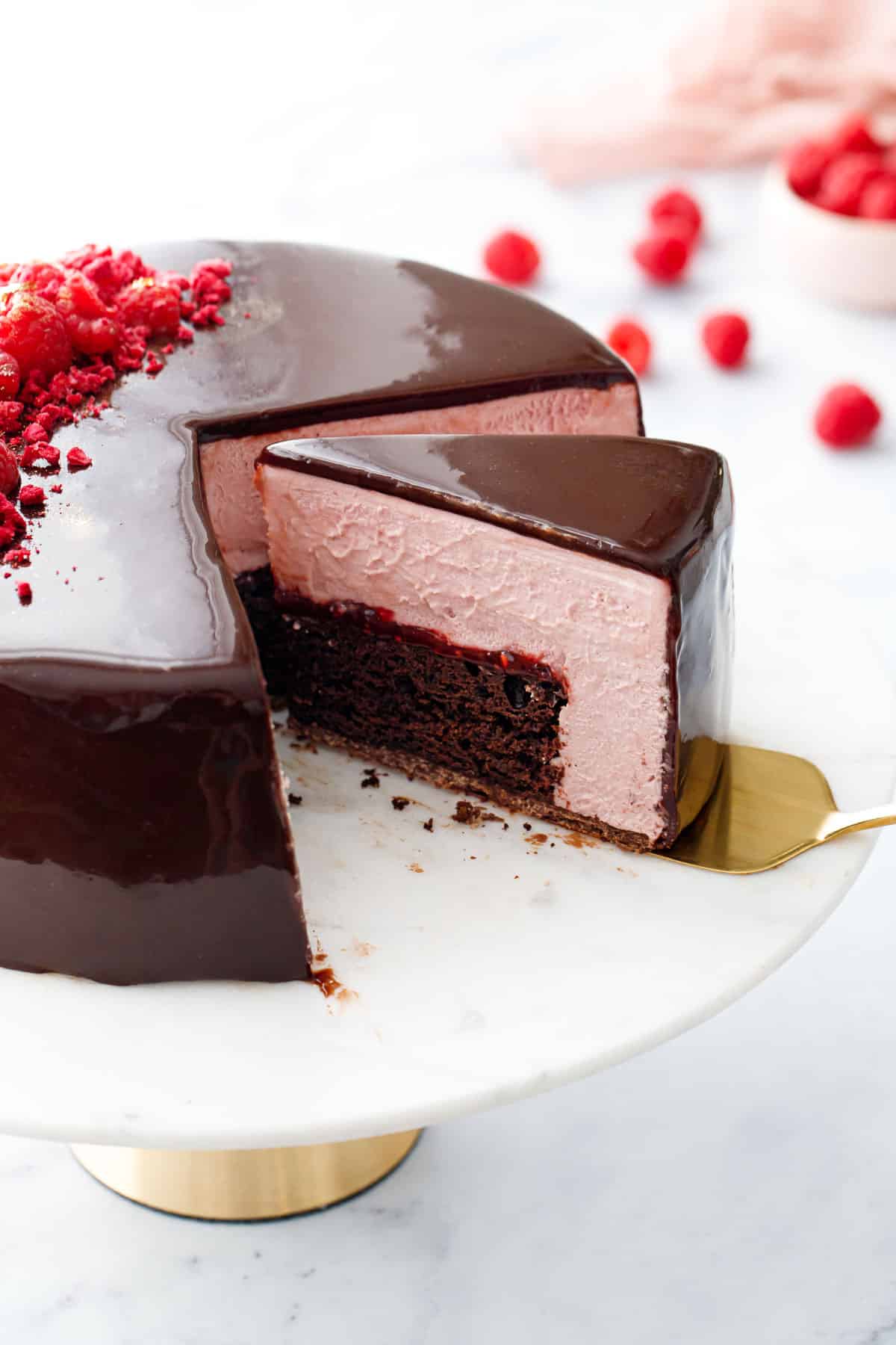 Slice of Chocolate Raspberry Mousse Cake showing the layers of chocolate cake, raspberry jam, and pale pink raspberry mousse inside.