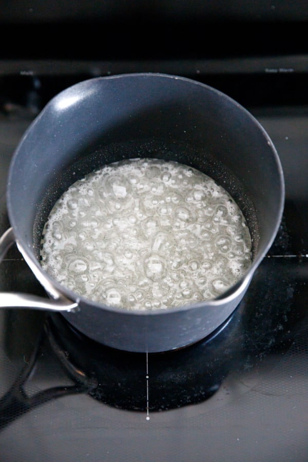Boiling mixture of sugar, water, and corn syrup in a saucepan.