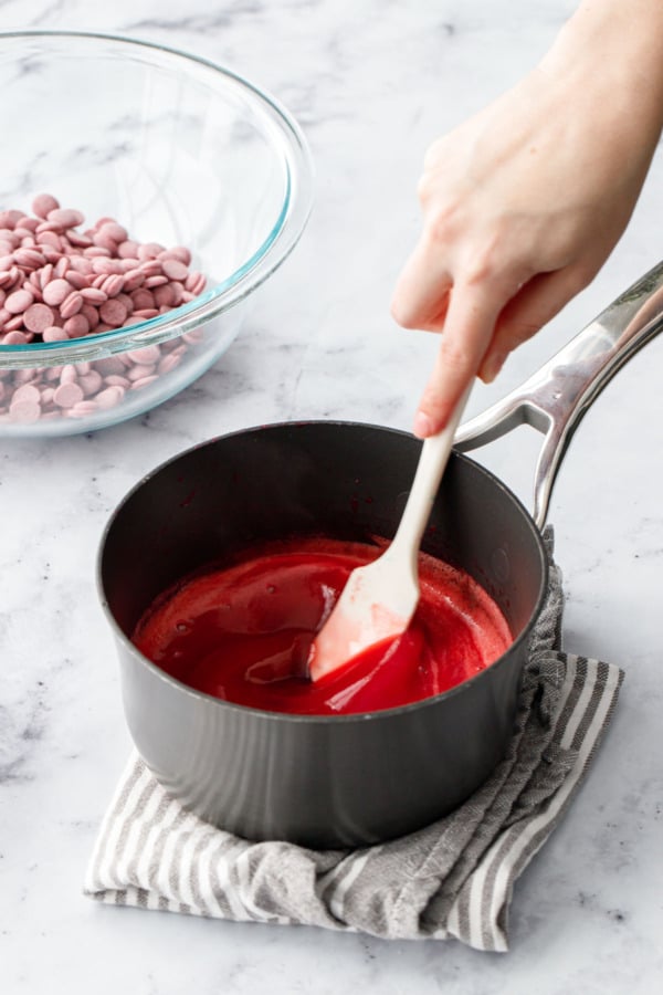 Stirring the softened leaf gelatin into the raspberry puree with a small spatula.