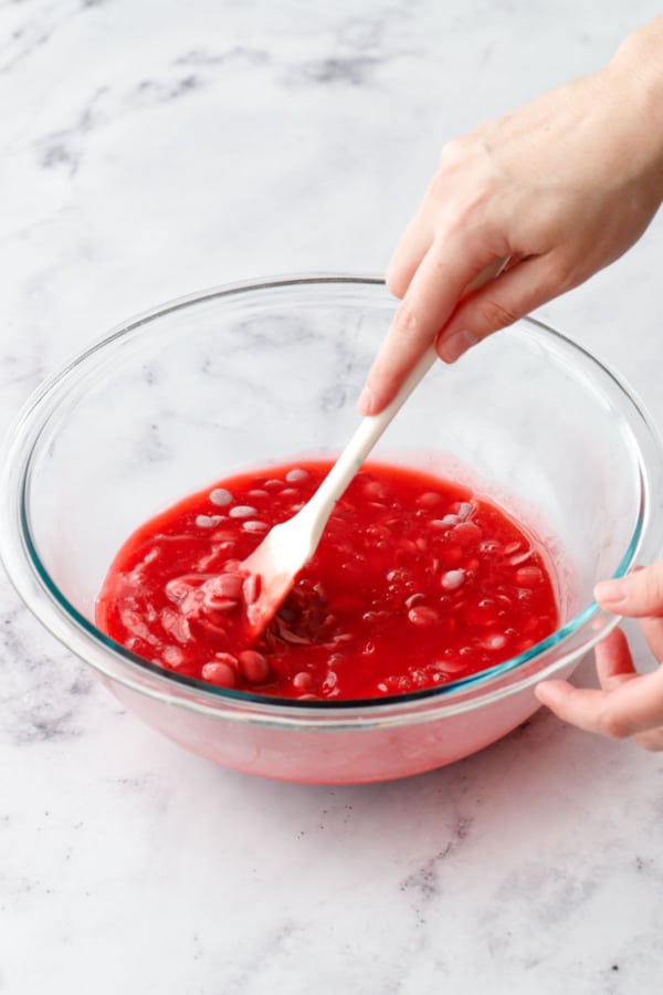Stirring raspberry and ruby chocolate with a small spatula until chocolate starts to melt.