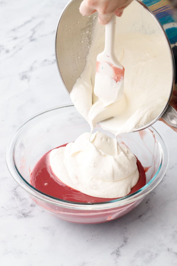 Adding soft dollops of whipped cream to bowl of raspberry and ruby chocolate.