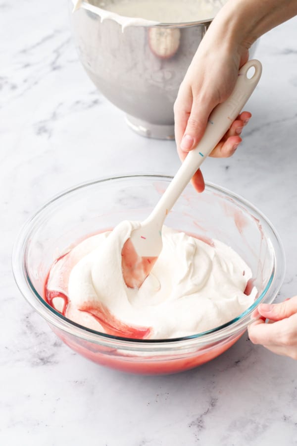 Gently folding whipped cream into raspberry mixture with a large rubber spatula to lighten the mixture.