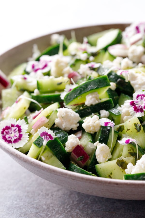 Closeup of Cucumber & Feta Salad with purple and white edible flowers