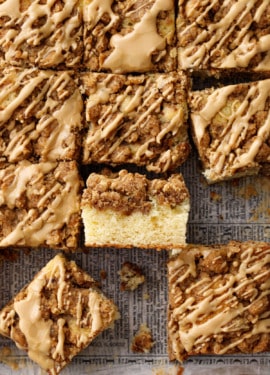 Overhead, grid of cut squares of coffee cake, one on its side to show the cake and crumb layers