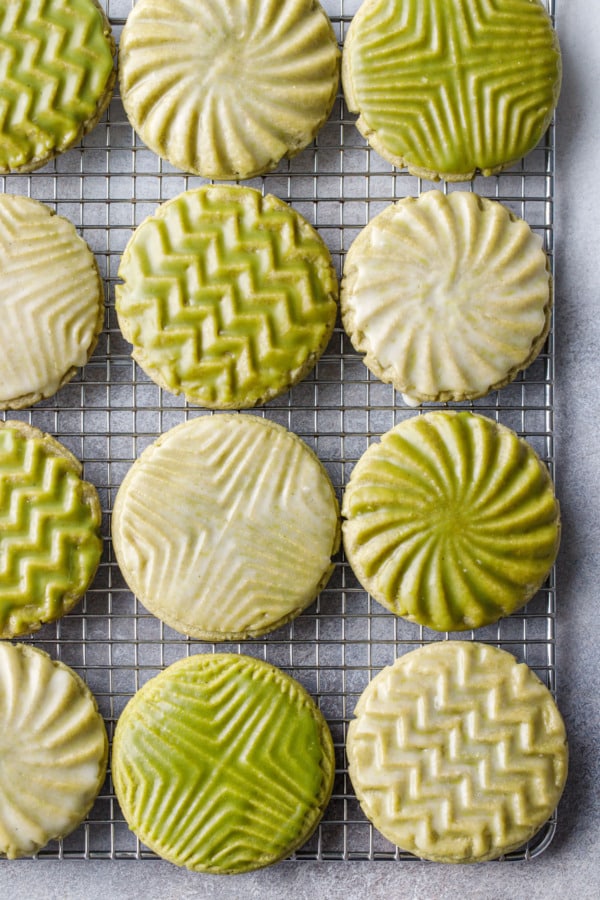 Overhead, wire rack with neat rows of Glazed Matcha Sugar Cookies with alternating white and green glazes and geometric designs.