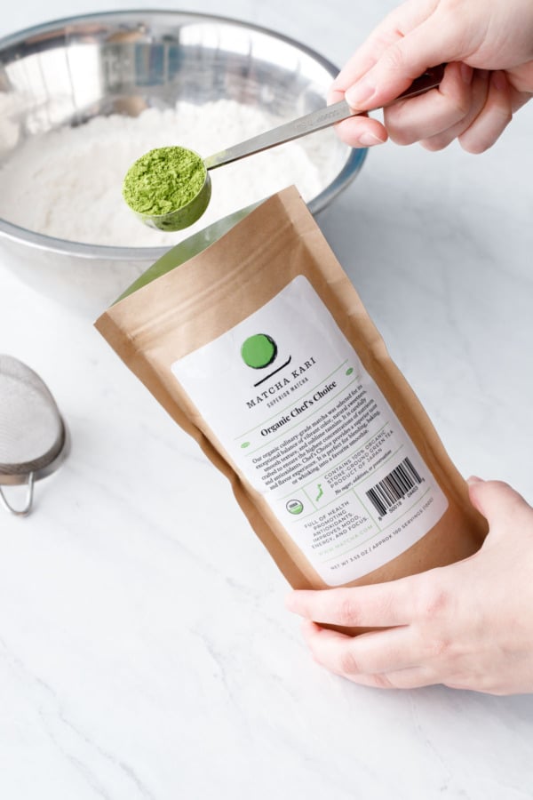 Scooping culinary matcha powder out of a brown package.