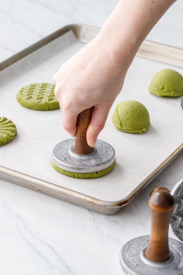 Using a cookie stamp to press the cookie into a 3/8-inch-thick round.