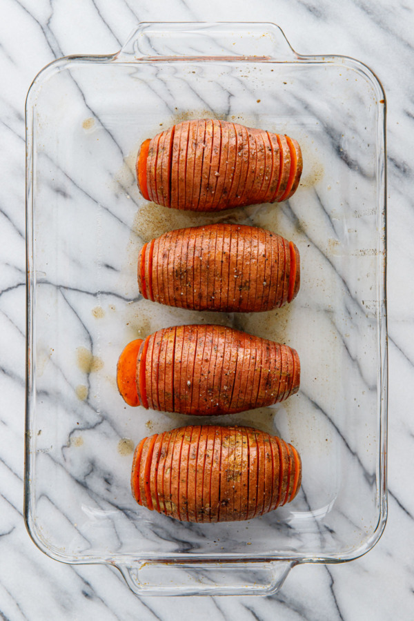 Spiced Hasselback Sweet Potatoes in a glass casserole dish, before baking