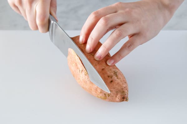Slicing the bottom off the sweet potato so it has a flat side.