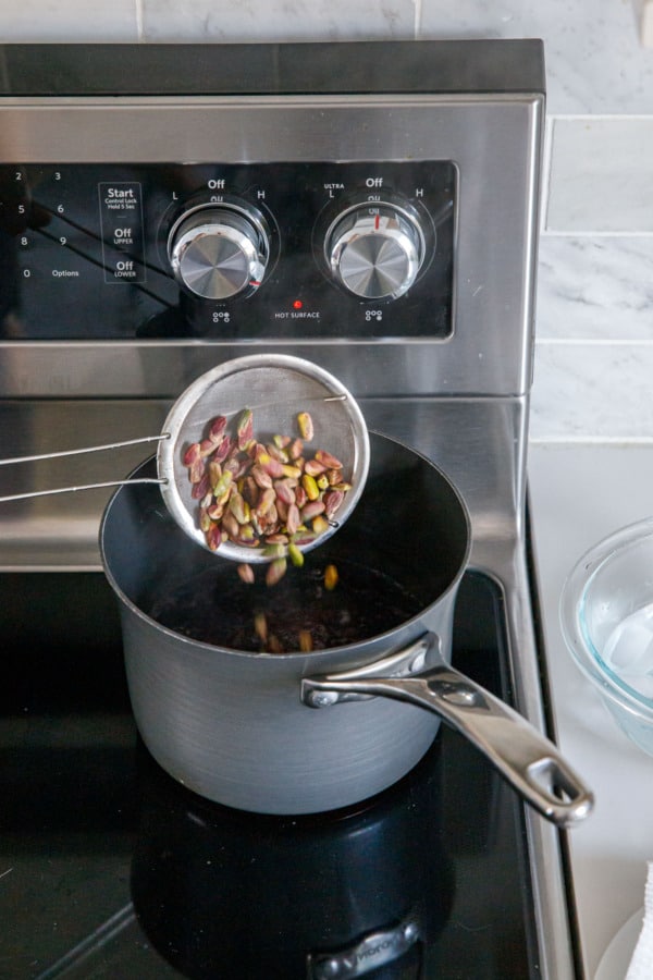 Blanching pistachios by dumping shelled nuts into a pot of boiling water.