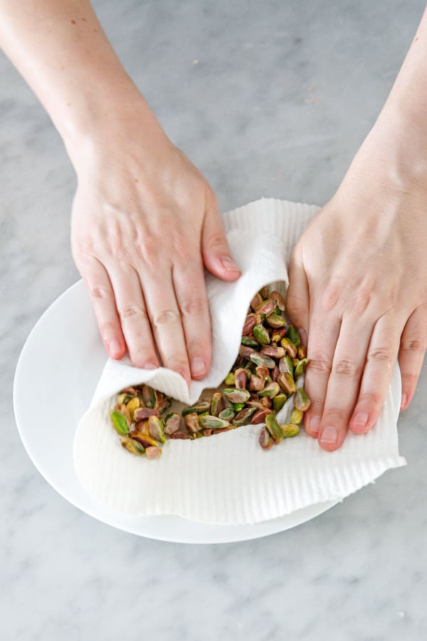 Rub the blanched pistachios between the cloth; the friction will help to remove and loosen the skins.