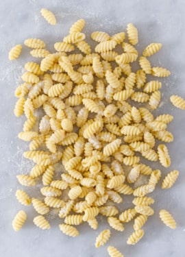 Overhead view pile of homemade gnochetti sardi pasta on a marble surface