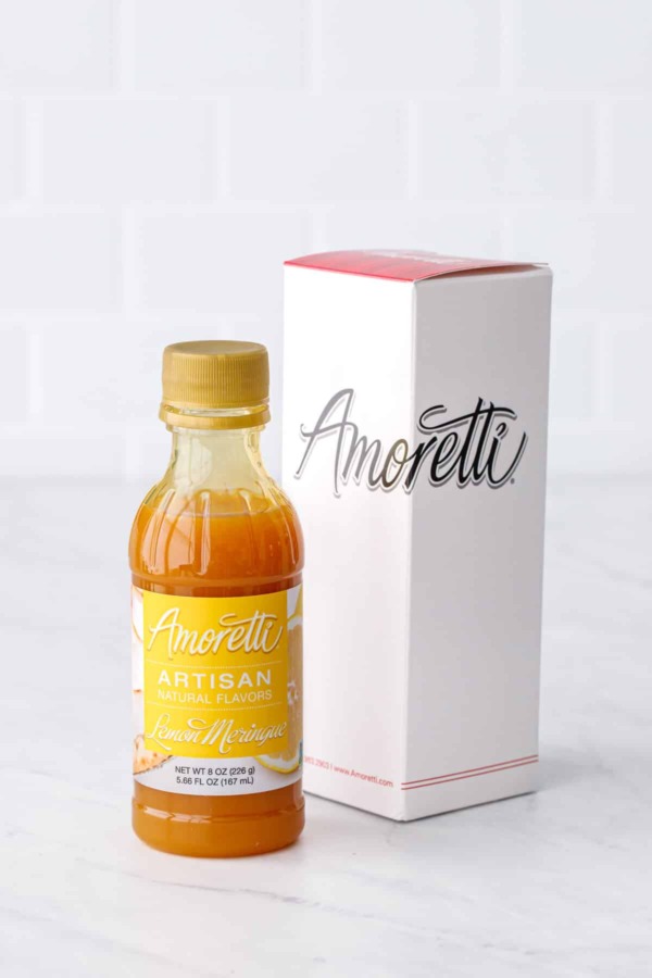 Bottle of Amoretti Lemon Meringue Artisan Flavoring with Amoretti box packaging on a white marble background.