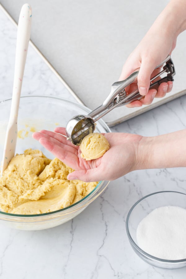 Releasing the ball of dough from the cookie scoop into the palm of a hand.