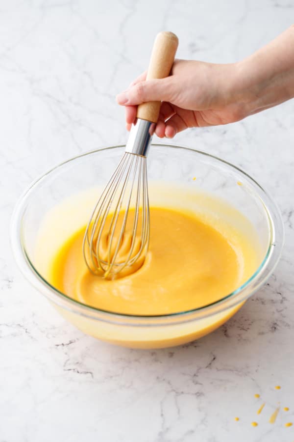 Whisking the Mango Lime Tart filling in a glass mixing bowl until smooth.
