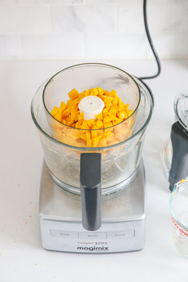Cubes of fresh mango in a food processor before pureeing.