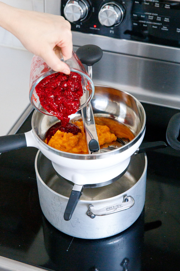 Pouring mashed raspberries and mangoes through a food mill.