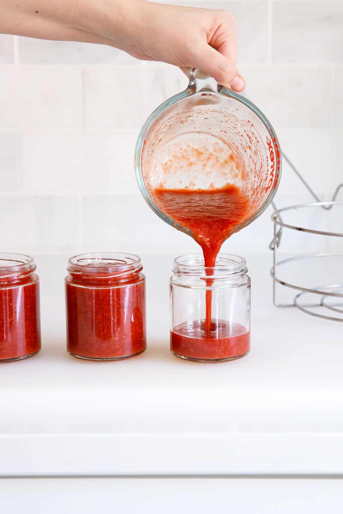 Dividing finished jam among glass jam jars.