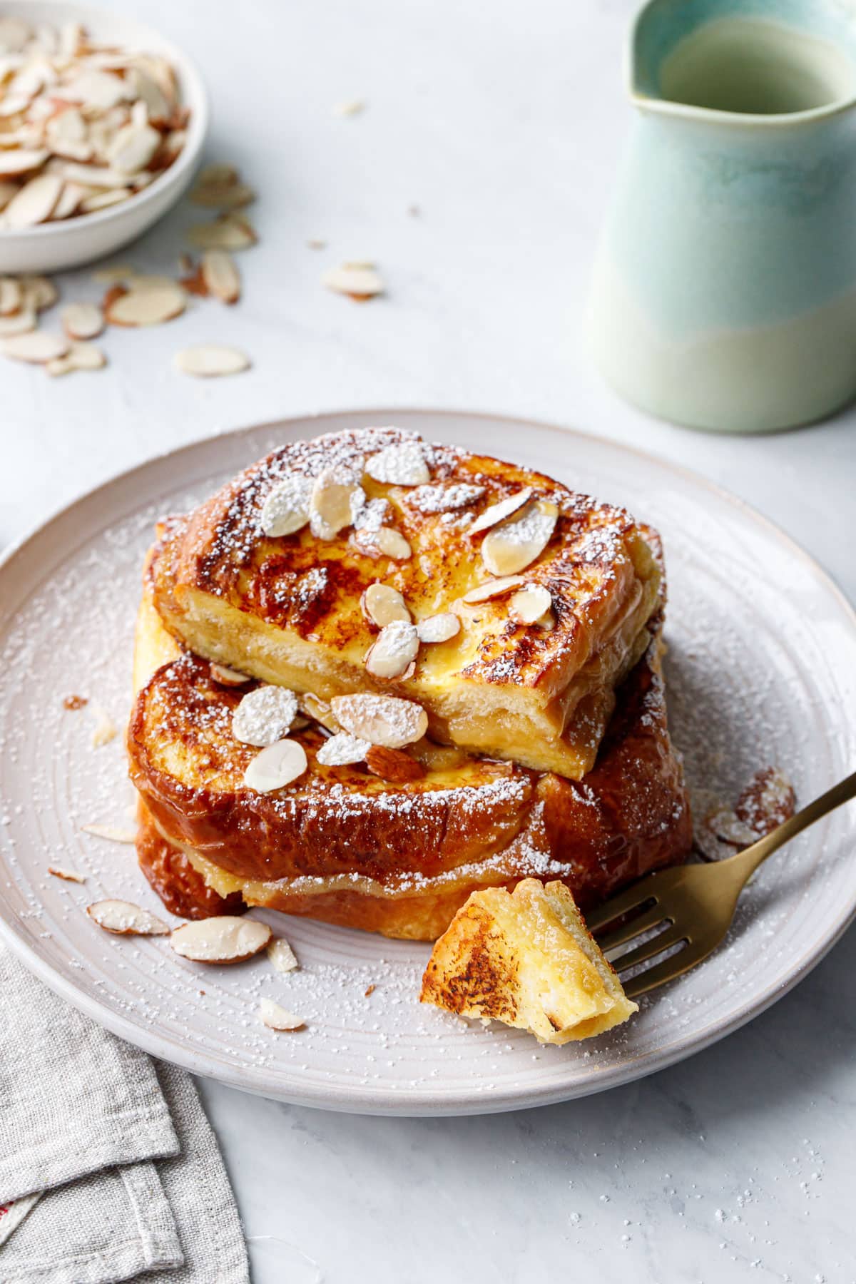 Plate with Marzipan-Stuffed French Toast, bite on a gold fork that shows the texture of the gooey filling inside.