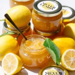Open jar of Old-Fashioned Meyer Lemon Marmalade, with whole and half lemons and full jars with printable labels.