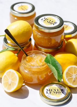 Open jar of Old-Fashioned Meyer Lemon Marmalade, with whole and half lemons and full jars with printable labels.