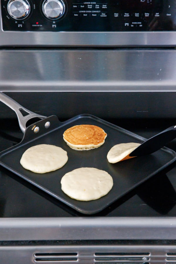 Flipping the pancakes with a thin spatula when the bottoms are golden brown.