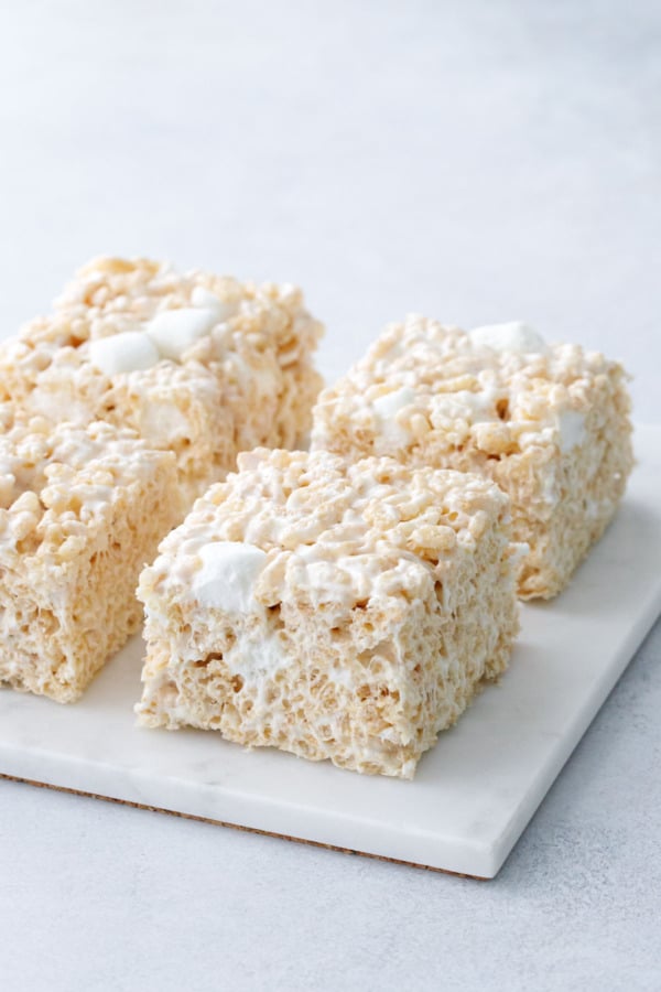 Four Olive Oil Rice Krispie Treats on a square marble trivet with gray background.