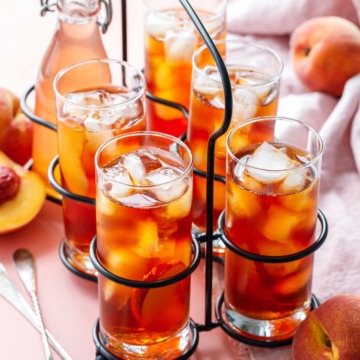 A vintage drink caddy with 5 glasses of Cold Brew Peach Iced Tea, and one bottle of peach sugar syrup