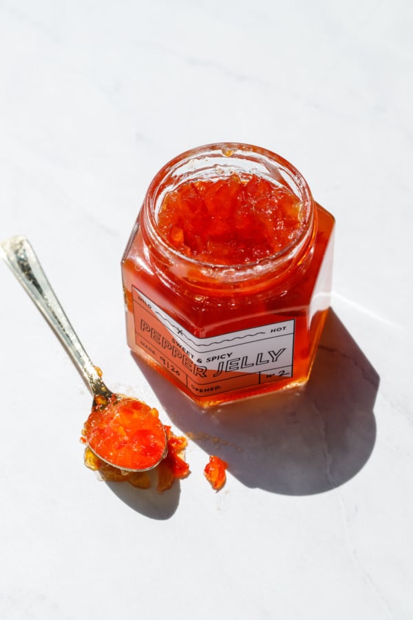 Harsh sunlight jar of red pepper jelly and a gold spoon