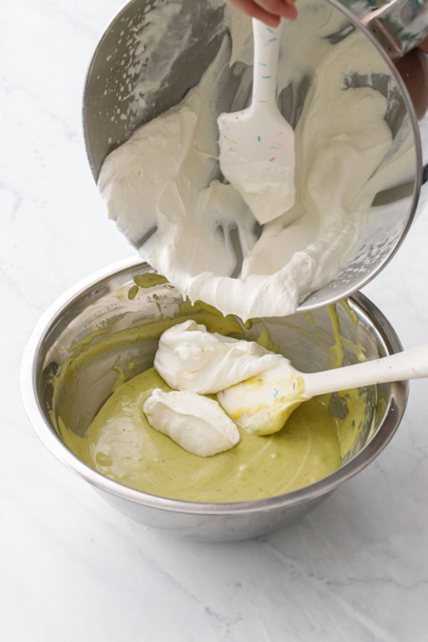 Adding the remaining whipped cream to the lightened pistachio cream mixture.