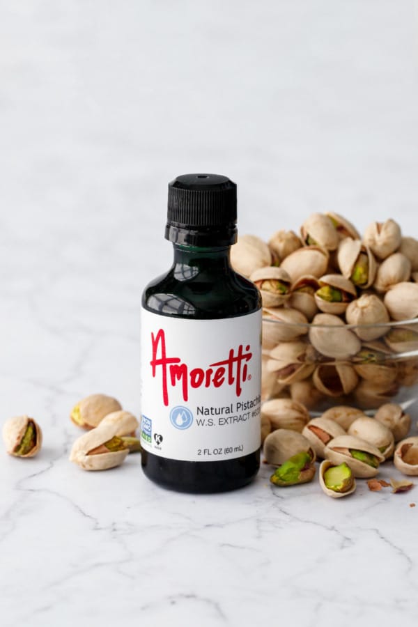 Amoretti Pistachio Extract bottle with bowl of pistachios.