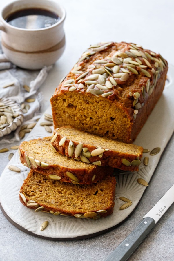 Spiced Pumpkin Banana Bread with three slices laying down, cup of coffee in the background.