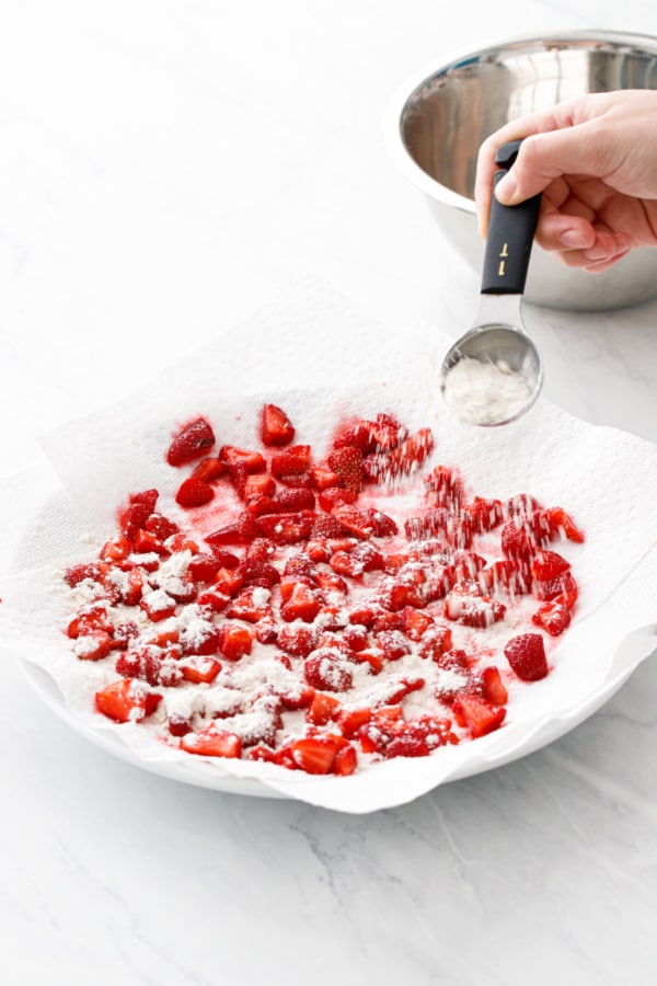 Sprinkling the strawberry pieces with flour to keep them from sticking together.
