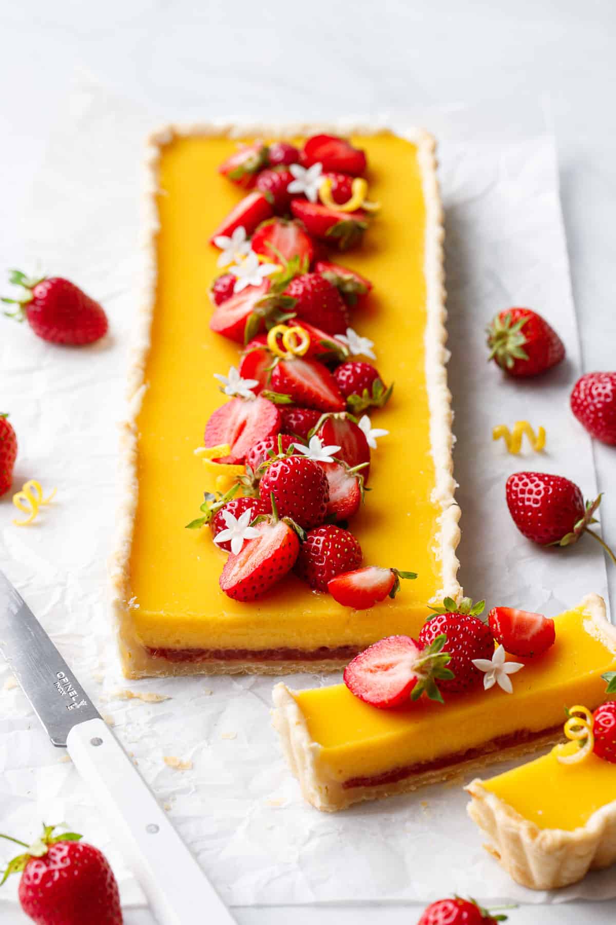 Strawberry Meyer Lemon Tart cut in slices to show the layer of strawberry jam at the bottom.