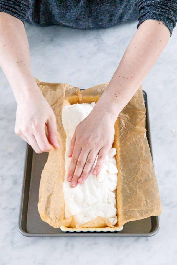 Fill parchment paper with weights such as granulated sugar to keep it from shrinking.