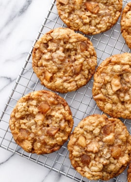 Overhead, wire rack with Toffee Apple Oatmeal Cookies on an angle, on a marble background